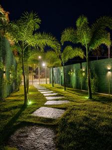 a garden at night with palm trees and a pathway at Luce del sole bangalô in Fortim +20 photos