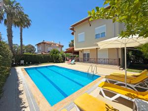 a swimming pool with two chairs and a house at Paradise Town Villa Orchard in Belek