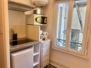a small kitchen with a microwave and a window at Studio -Center - Lorient in Lorient