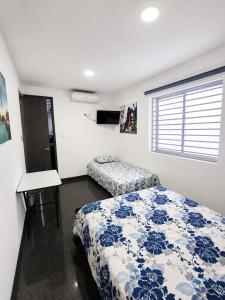 a bedroom with a bed and a desk and a window at Hotel Siglo 21 in Cali