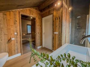 a bathroom with wooden walls and a tub and a sink at Nockberge in Afritz +28 photos
