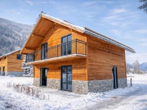 a log cabin in the snow with a balcony at Alpenzeit Afritz am See in Afritz