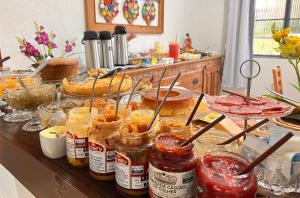 a table with many jars of jam and pies at Pouso das Flores - Próximo a Maria Fumaça in Tiradentes