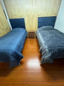 a bedroom with two beds and a wooden floor at Habitación Hostal Refugio Gaucho in Cochrane
