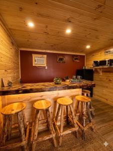 a bar in a cabin with four wooden stools at The Lake George Inn in Lake George