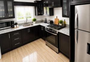 a kitchen with black cabinets and stainless steel appliances at Glenmuir La Ville - Gated Com May Pen in May Pen