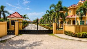 a gate to a house with palm trees at Glenmuir La Ville - Gated Com May Pen in May Pen