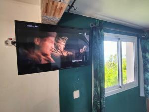 a flat screen tv hanging on a wall with a window at Studio Évasion - Vue imprenable sur la mer in Le Marin