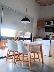 a kitchen with a dining room table and white chairs at Trovare un Senso in Capilla del Monte +11 photos