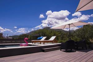 a deck with a pool with chairs and an umbrella at Trovare un Senso in Capilla del Monte