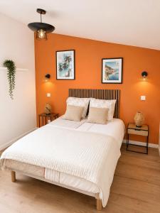 a bedroom with a large bed with an orange wall at Le Refuge de Chateau Renard in Château-Renard