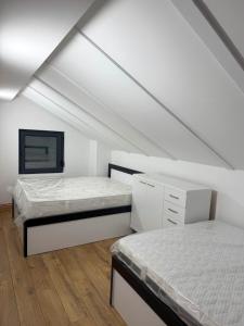 two beds in a room with white walls and wood floors at Villa NOA in Bijeljina