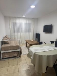 a bedroom with two beds and a table and a window at Amelie 4 in General Roca