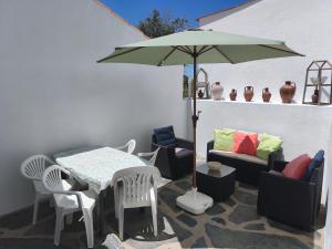 a patio with a table and chairs and an umbrella at Casa da Roda in Arronches