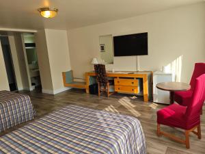 a hotel room with a bed and a desk and a tv at Auberge Cap Martin in La Pocatiere