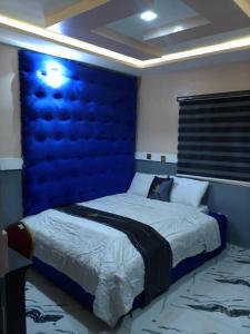 a bedroom with a large bed with a blue headboard at Emmydon Hotel And Suites in Enugu +5 photos