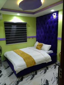 a bedroom with a large bed with a purple headboard at Emmydon Hotel And Suites in Enugu