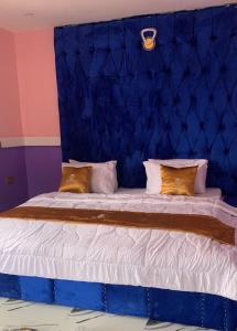 a large bed with a blue headboard and pillows at Emmydon Hotel And Suites in Enugu