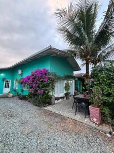 a blue house with a table and a palm tree at Pousada Anturio Centro in Barra Velha