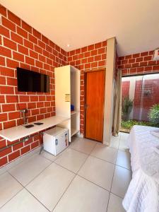 a bedroom with a brick wall with a desk and a television at Pousada Martins Turismo in Carolina