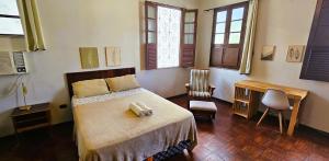 a bedroom with a bed and a desk and windows at Casa 307 in Manaus