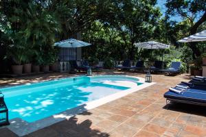 a swimming pool with blue chairs and umbrellas at Il Piccolo Peccato in Cuernavaca