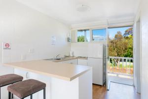 a white kitchen with a refrigerator and a window at Summer East Apartments in Orange