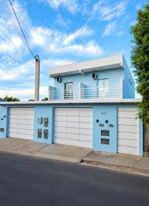 a blue house with white garage doors on a street at Casa Harmonia - Ar Condicionado in Bom Jesus da Lapa