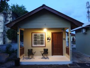 a small house with a front porch with two chairs at IA Tiny House 2 in Dungun +6 photos