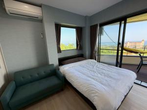 a bedroom with a bed and a couch and windows at Villa resort -悠- in Miyakojima
