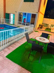 a patio with a table and chairs and a pool at استراحة الرايس in Rayyis