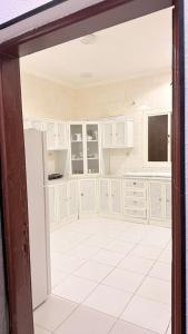 a kitchen with white cabinets and a television at استراحة الرايس in Rayyis