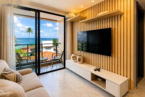a living room with a television on a wall at Beachfront flat at Porto de Galinhas beach, close to the natural pools. in Porto De Galinhas