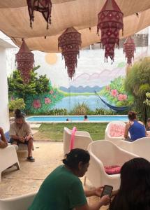 a group of people sitting in chairs in front of a mural at Güemes Hostel Cordoba in Córdoba