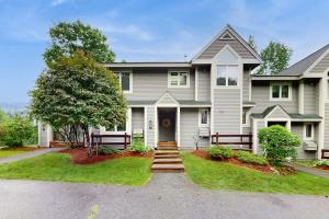 a large white house with a tree and stairs at Loon Mountain Condo in Lincoln