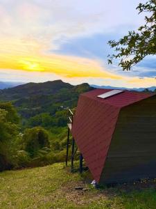 a shed with a red roof on top of a hill at La Nebulosa Glamping in Vergara +17 photos
