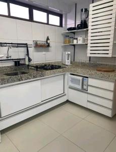 a large kitchen with white counters and appliances at Apt Completo com Vista para o Mar, Ar Condicionado e Café da Manhã Opcional in Recife