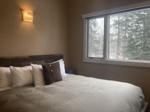 a bedroom with a white bed with a window at Moose Creek Lodge in Wilson
