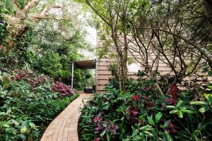 a garden with pink flowers and a brick walkway at Family & Friends Cottage in Mount Tamborine
