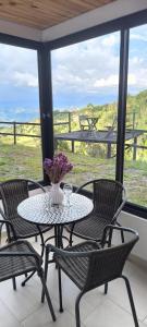 a table with chairs and a vase of flowers on a porch at La Nebulosa Glamping in Vergara