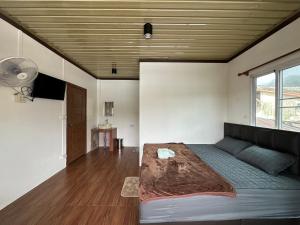 a bedroom with a large bed and a fan at ปิล๊อกพอเพลิน-pilokporploen in Ban Pilok Khi