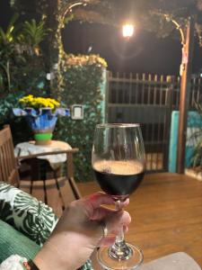 a person holding a glass of red wine at Pousada Anturio Centro in Barra Velha