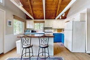 a kitchen with a refrigerator and two bar stools at The Beech Cottage in Tuftonboro