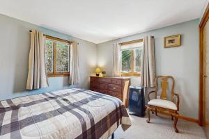 a bedroom with a bed and a dresser and windows at Wiggly Bridge Landing in York Harbor