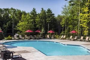 a swimming pool with chairs and umbrellas at Coral Drift Cottage in Wells