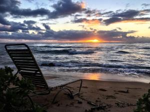 a beach chair sitting on the beach at sunset at Oceanfront Studio at Islander on the Beach #325 in Kapaa
