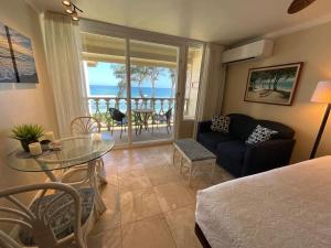 a living room with a bed and a glass table at Oceanfront Studio at Islander on the Beach #325 in Kapaa