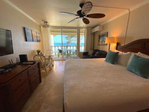 a bedroom with a large bed with a ceiling fan at Oceanfront Studio at Islander on the Beach #325 in Kapaa +27 photos