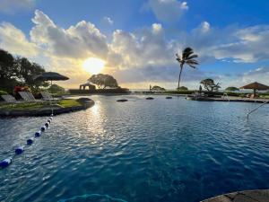 a pool at a resort with the sun setting at Oceanview Studio at Kauai Beach Resort #2444 in Lihue