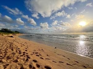 a beach with footprints in the sand and the ocean at Oceanview Studio at Kauai Beach Resort #2444 in Lihue